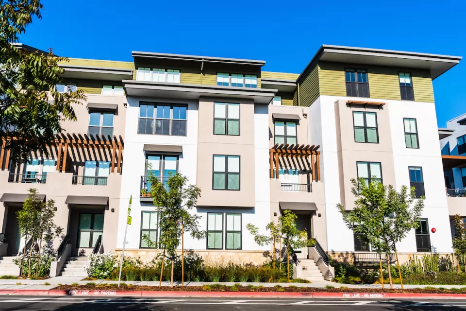 Four-story light-colored multifamily apartment building.